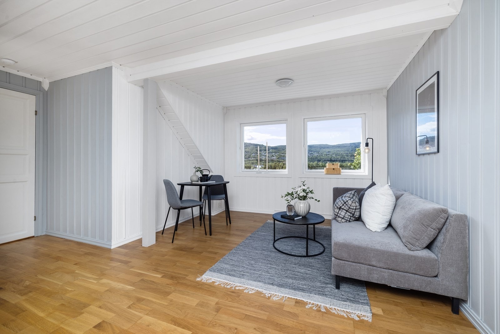 Lys stue med plass til en liten sofagruppe og spisebord i 2. etasje. Galleribilde
