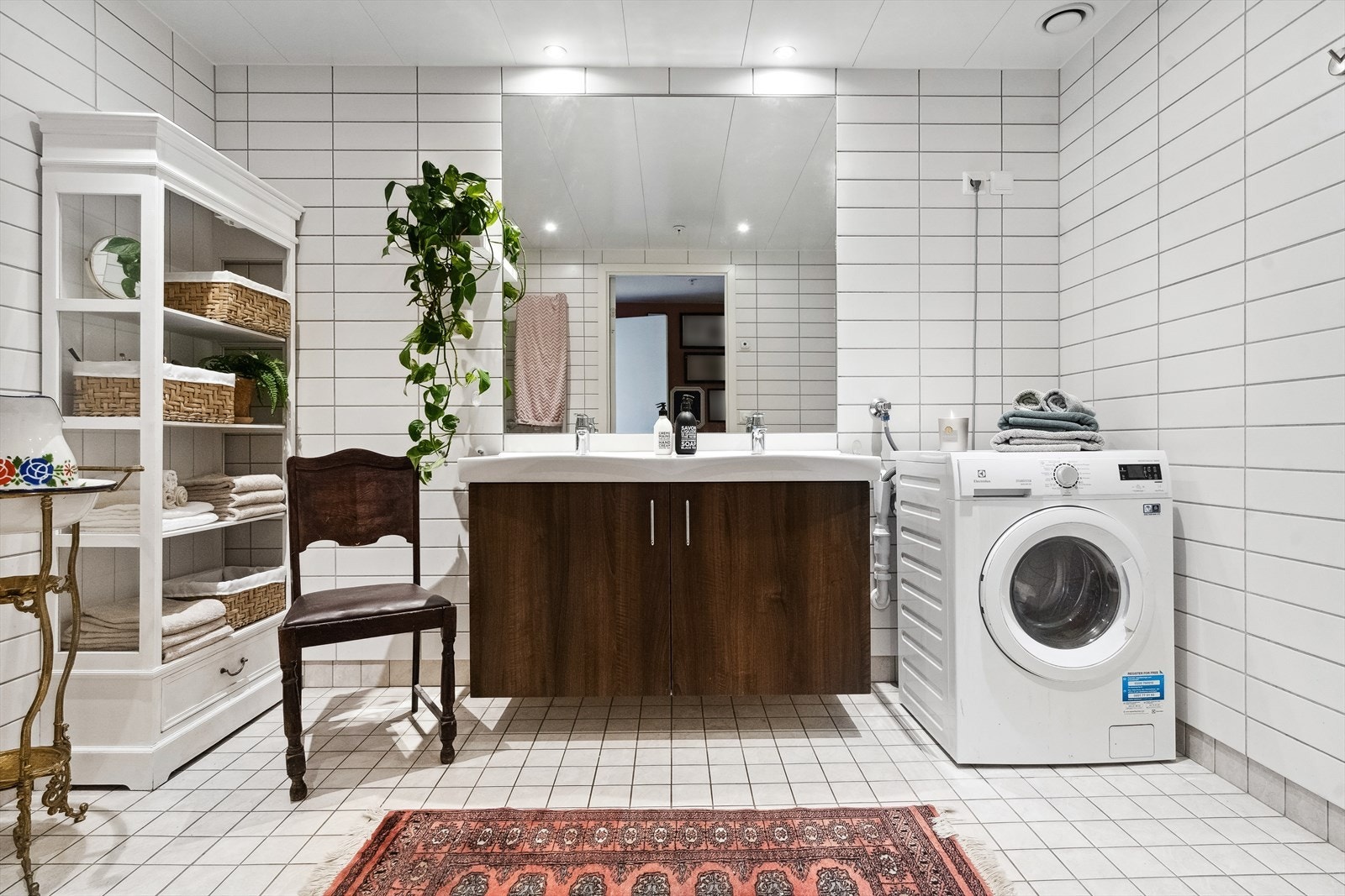 Badet er helfliset og har varme i gulv. Her er stor baderomsinnredning med dobbel servant, stort speil, veggmontert wc og opplegg for vaskemaskin/tørketrommel. Galleribilde