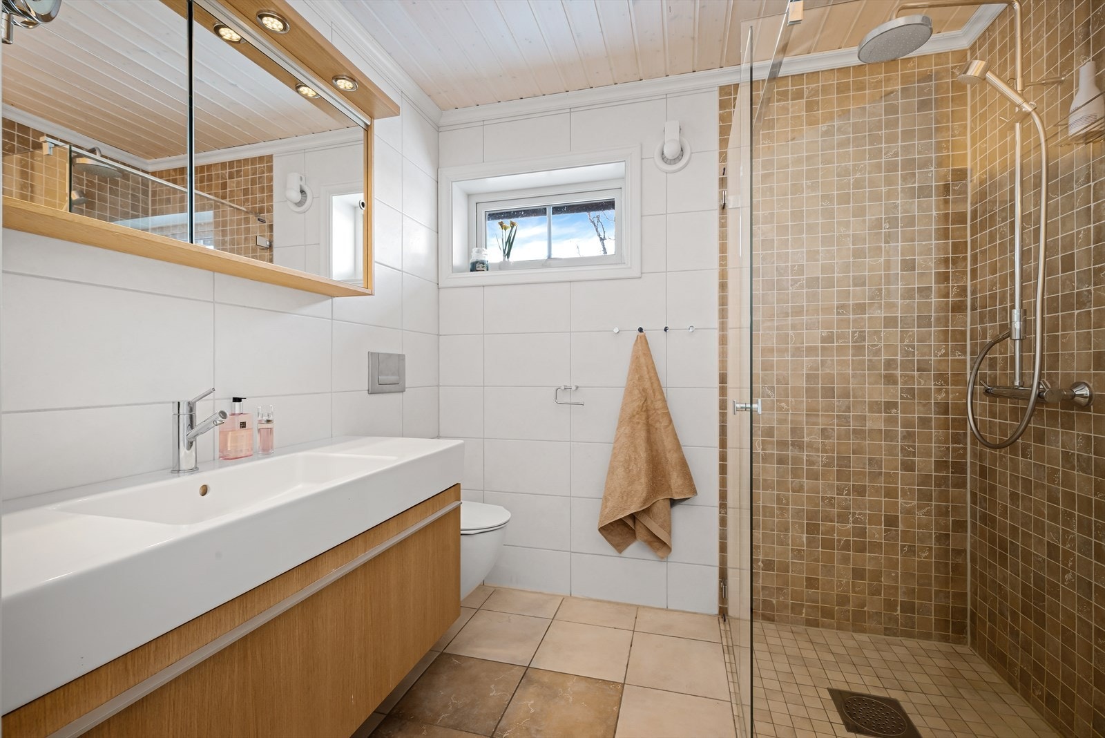 Hytta har to bad, og dette badet har adkomst fra gangen. Rommet har fliser, gulvvarme og dusjhjørne med regndusj. Galleribilde