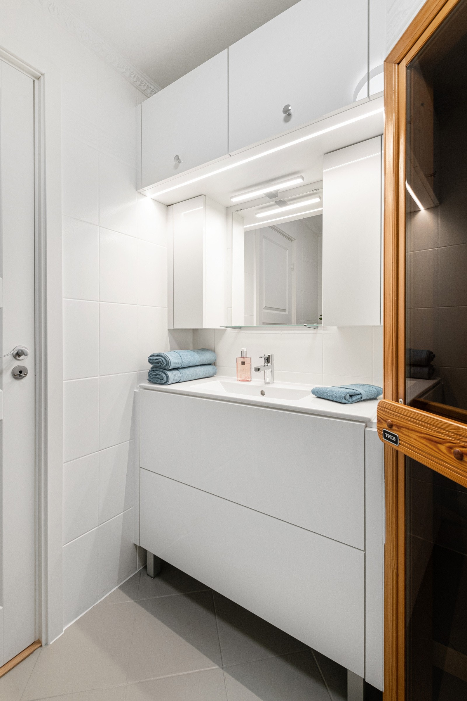 Baderomsinnredningen har slette fronter, og den inkluderer praktiske elementer som et speil, skap og belysning over servanten. Galleribilde