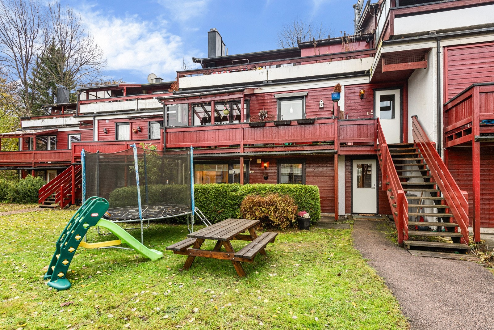 Fellestomt opparbeidet med blant annet: Asfalterte internveier, gressplen, trær, prydbusker og diverse beplantning. Det er satt opp en støyskjerm mot Strømsveien. Galleribilde