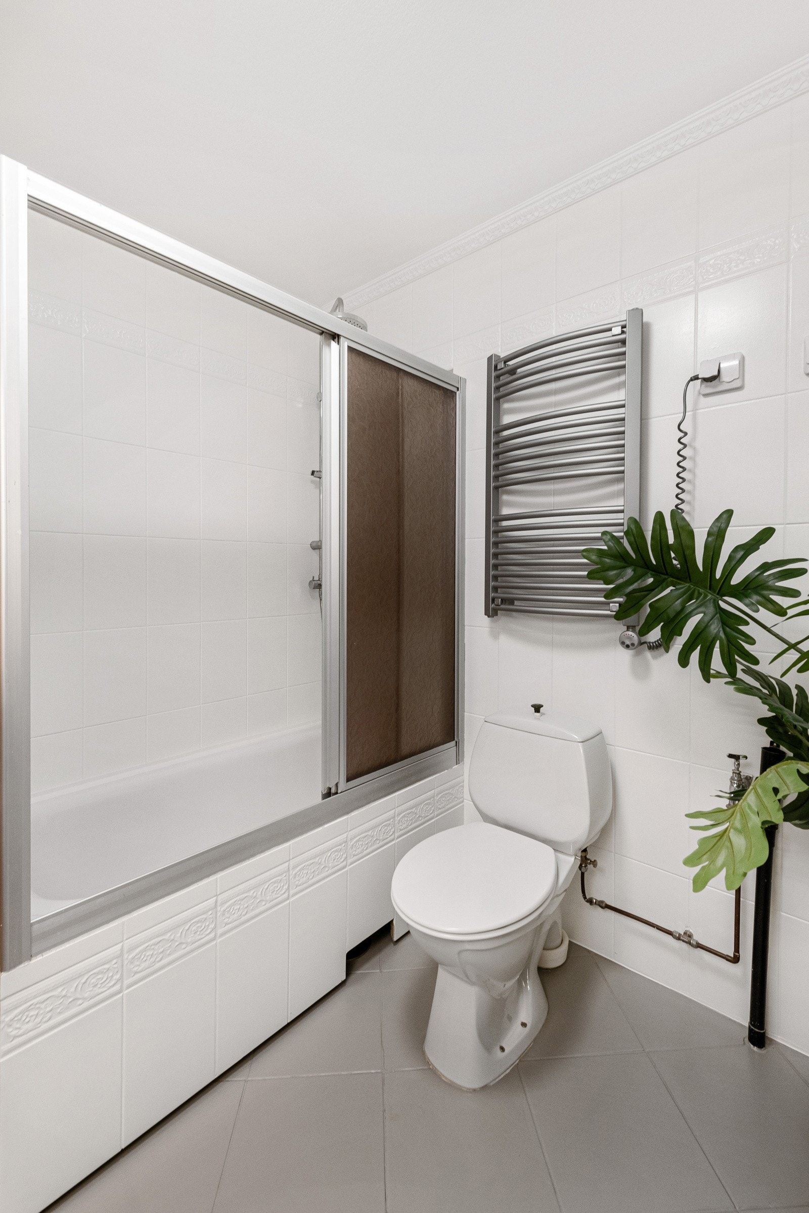 Innmurt badekar med skillevegg og har dusjarmatur tilkoblet hånddusj og regndusj. Baderom med frittstående toalett. Galleribilde