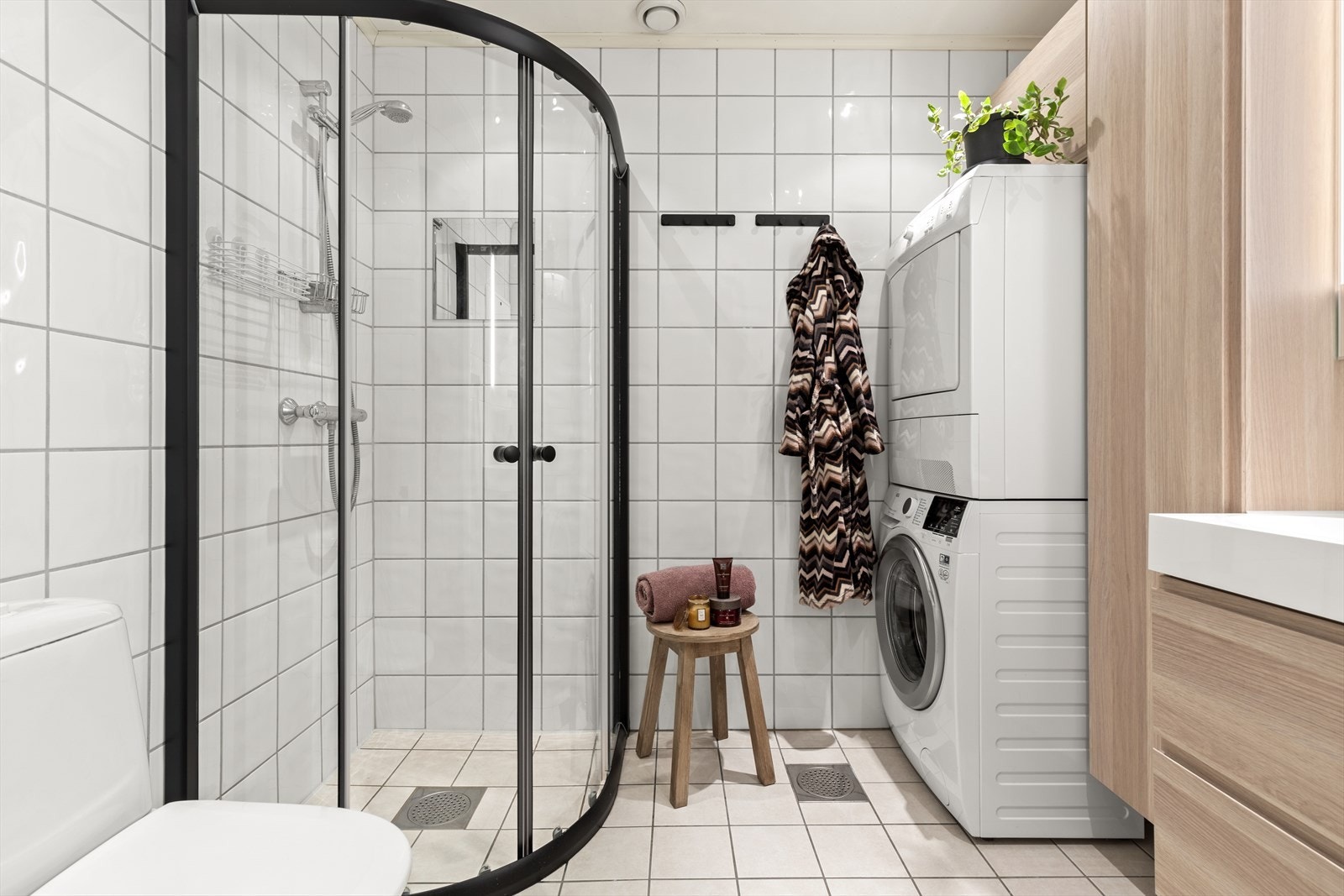 Stilrent bad med flislagte vegger og himling med downlights. Dusjhjørne med svingbare glassdører og gulvstående toalett. Galleribilde