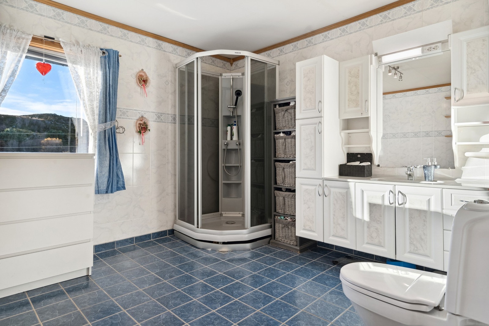 Badet er av god størrelse med varmekabler og fliser på gulvet og aquatile-plater på vegger. Galleribilde
