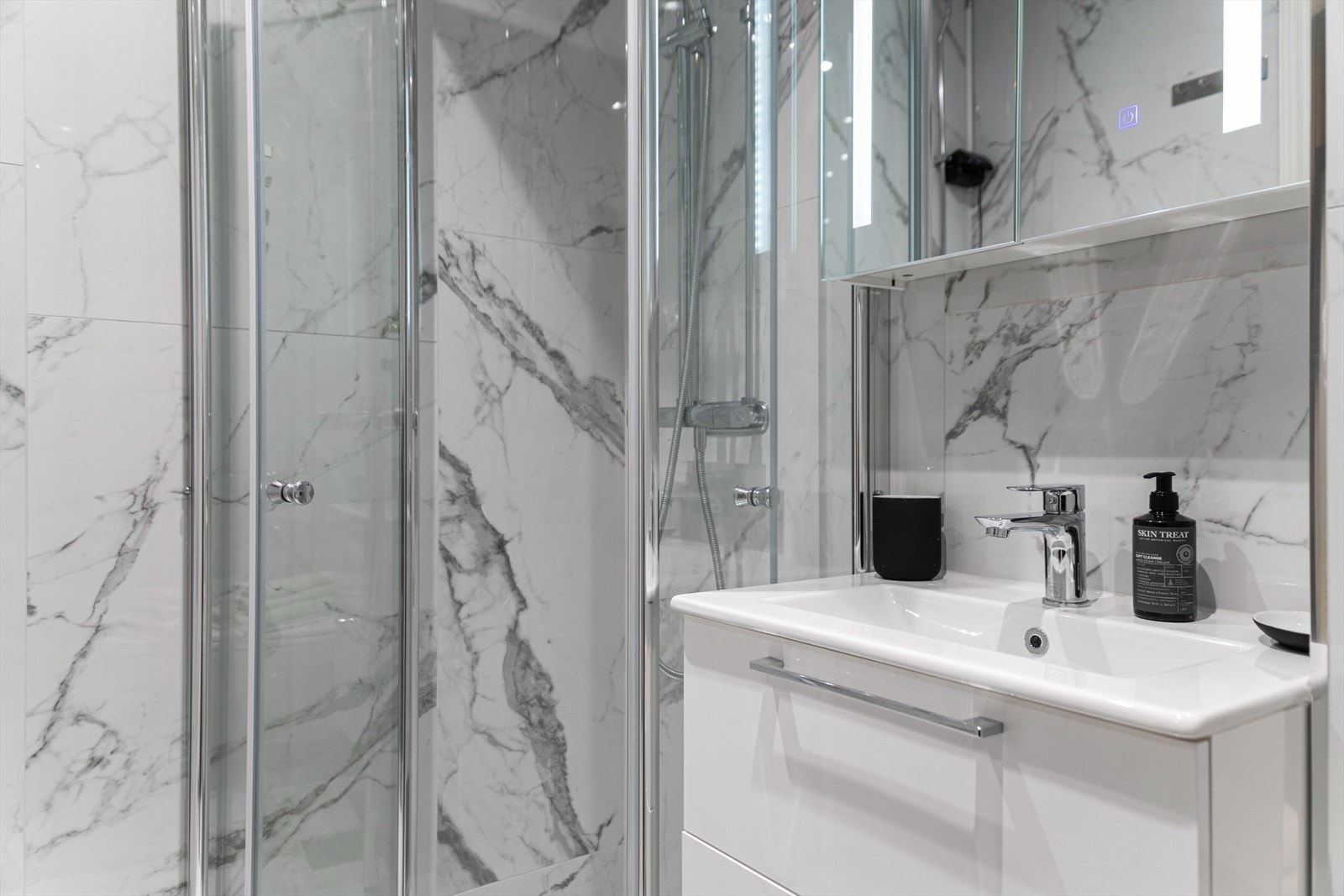 Badet inneholder ny innredning fra 2023 som vegghengt wc, servantskap med ett-greps blandebatteri, belyst speilskap på vegg, og opplegg for vaskemaskin Galleribilde