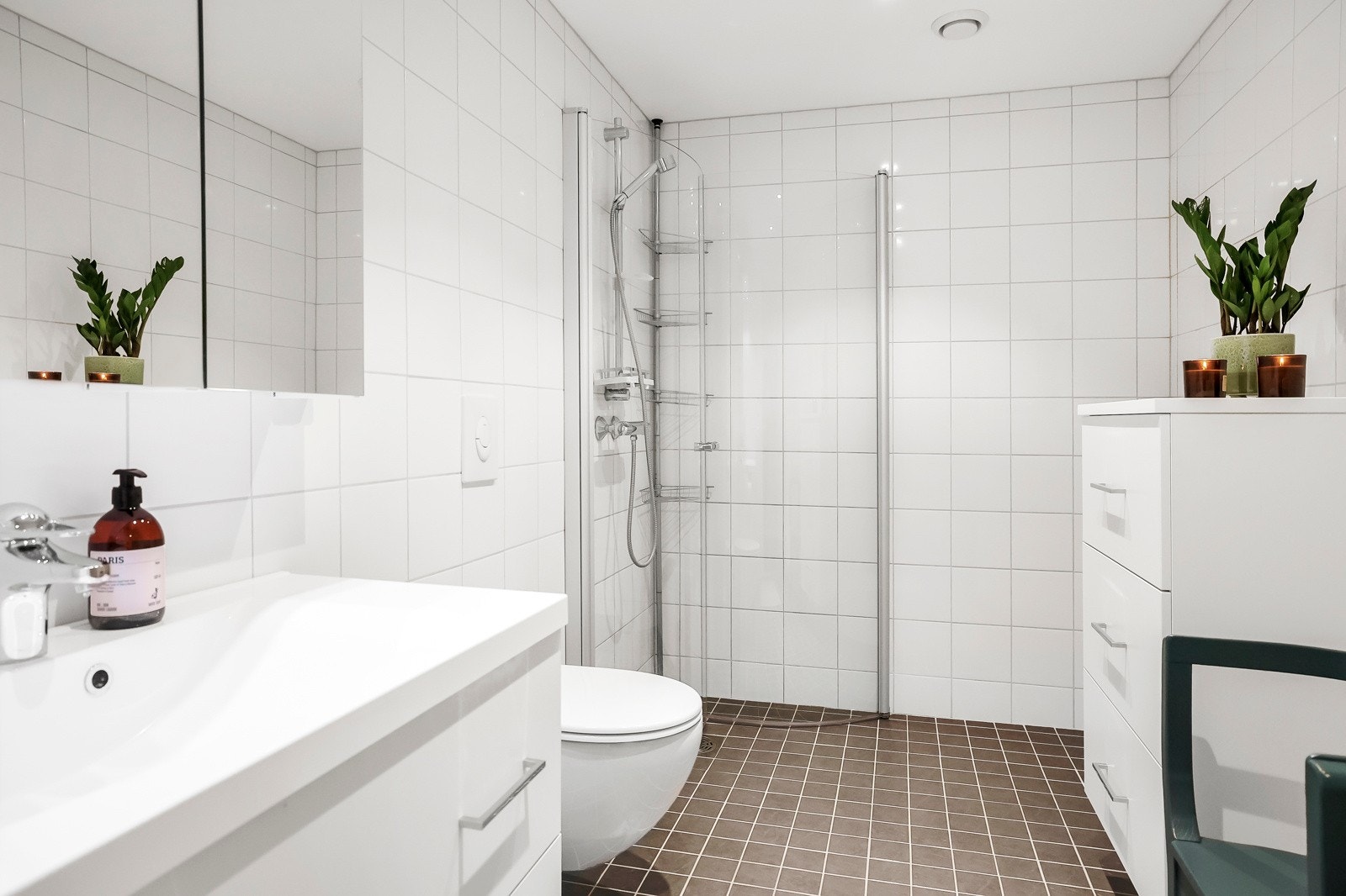 Baderommet har grå gulvfliser med vannbåren varme og hvite veggfliser. Det er downlights i tak Galleribilde