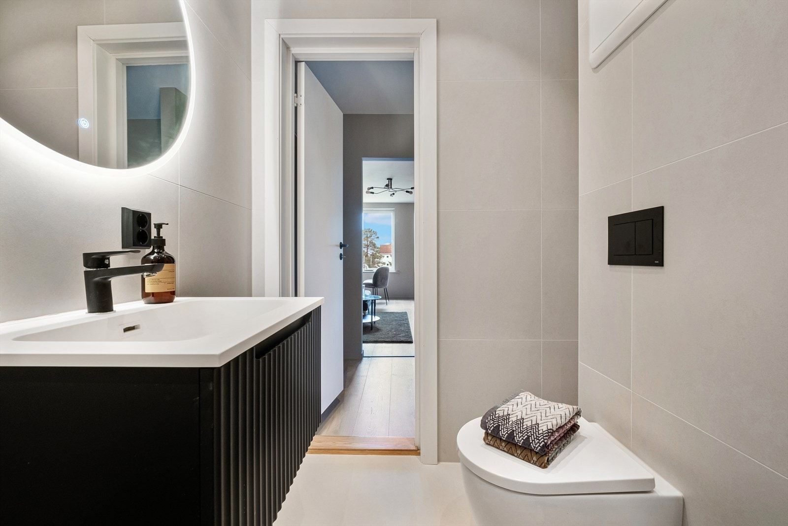 Badet har innredning og garnityr som består vegghengt toalett, baderomsinnredning med skuff, nedfelt servant og speil med belysning, dusjhjørne med innfellbare glassdører Galleribilde