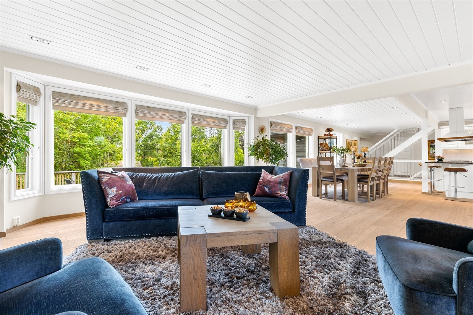 Delikat og stor stue med 1-stavs heltre rustikk parkett på gulv med up-lights, og malt panel i tak med innfelt downlights Galleribilde