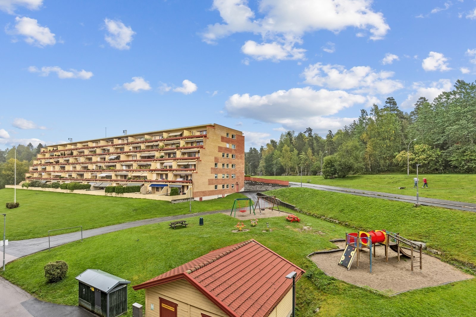 Fellesarealer med lekeplass og samlingspunkt med grill og flere sitteplasser i umiddelbar nærhet. Galleribilde