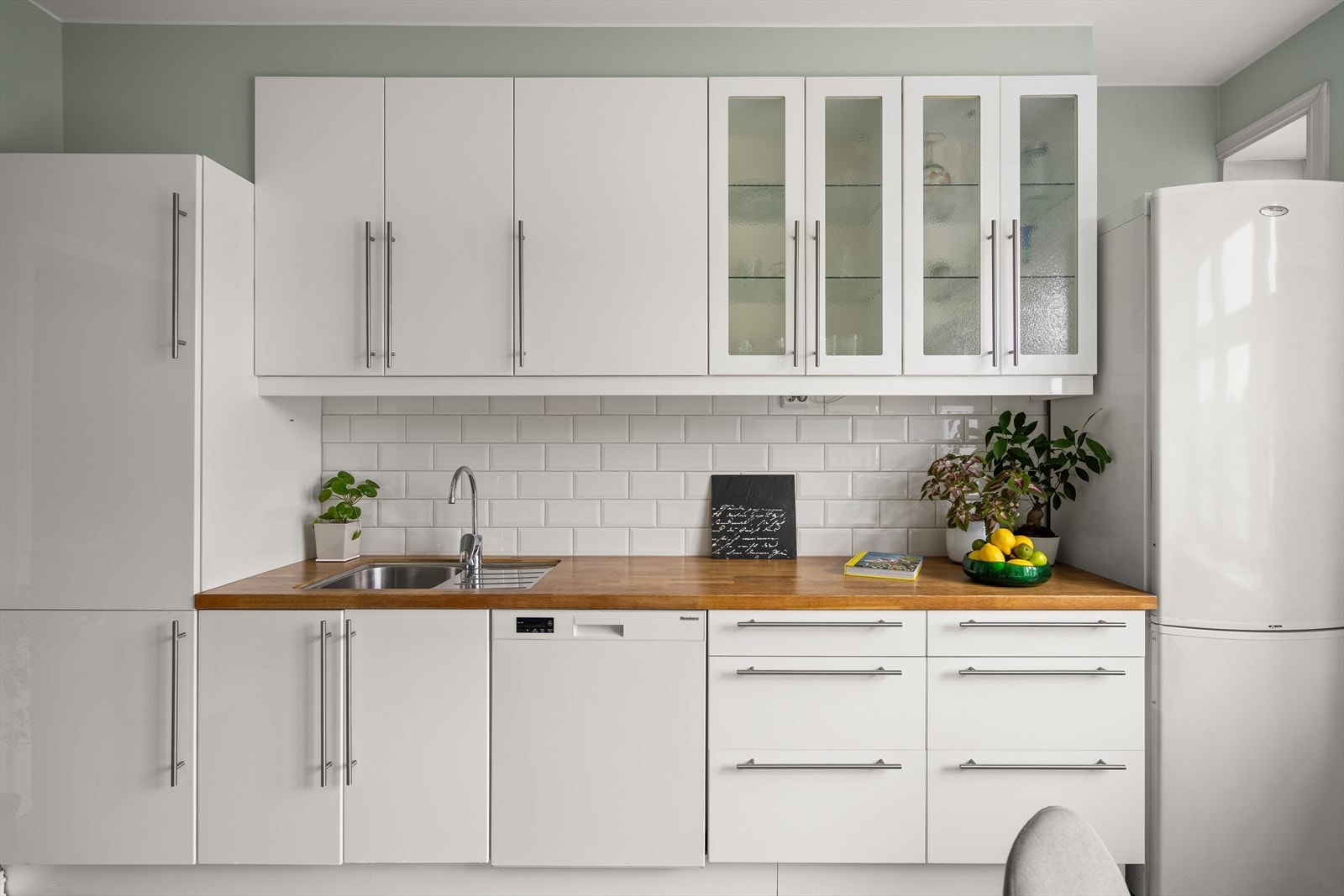 Kjøkkeninnredningen består av hvite glatte fronter, benkeplater i heltre, fire dører med glass, underlimt oppvaskkum, ventilator i stål med kullfilter og opplegg for oppvaskmaskin. Galleribilde