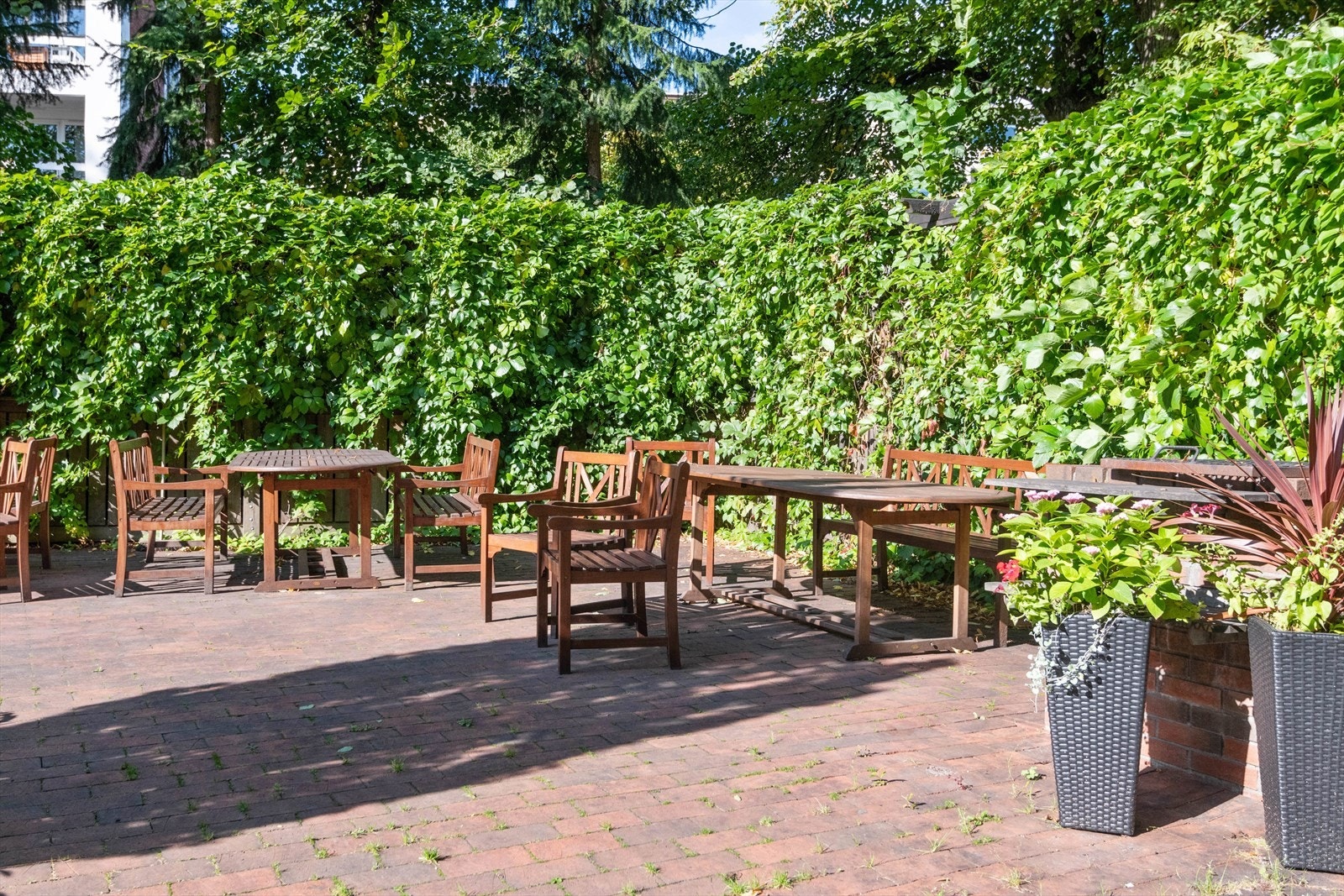 Pent opparbeidet fellesareal i kvartalsbebyggelse med asfalterte adkomstveier/plasser, steinbelagte arealer, gressplen, beplantning, trær, sittegrupper, lekeapparater m.m. Galleribilde