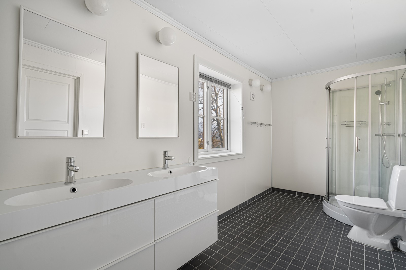 Delvis flislagt lyst bad med dobbelservant.