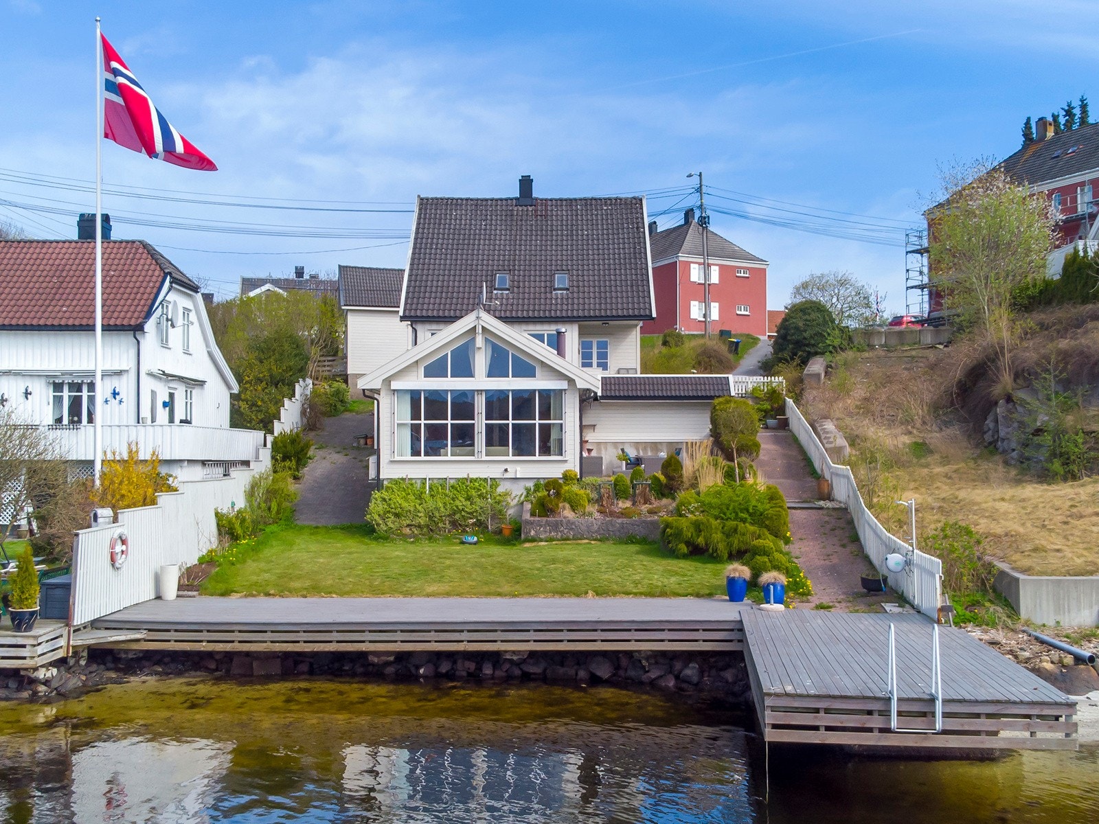 Tomten er opparbeidet med belegningsstein, plenareal, blomsterbedd, terrasser og brygge. Galleribilde