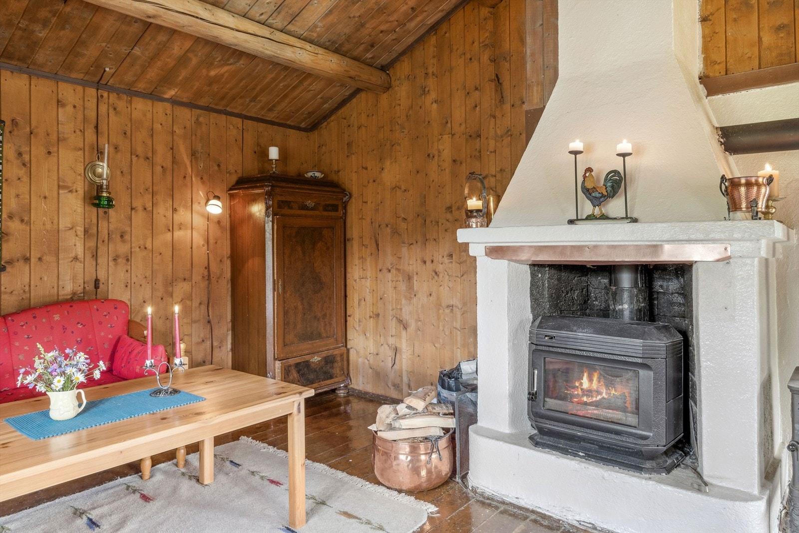 Stua har lakkert tregulv og panel på vegger. Mønet himling med tømmeråser. Galleribilde