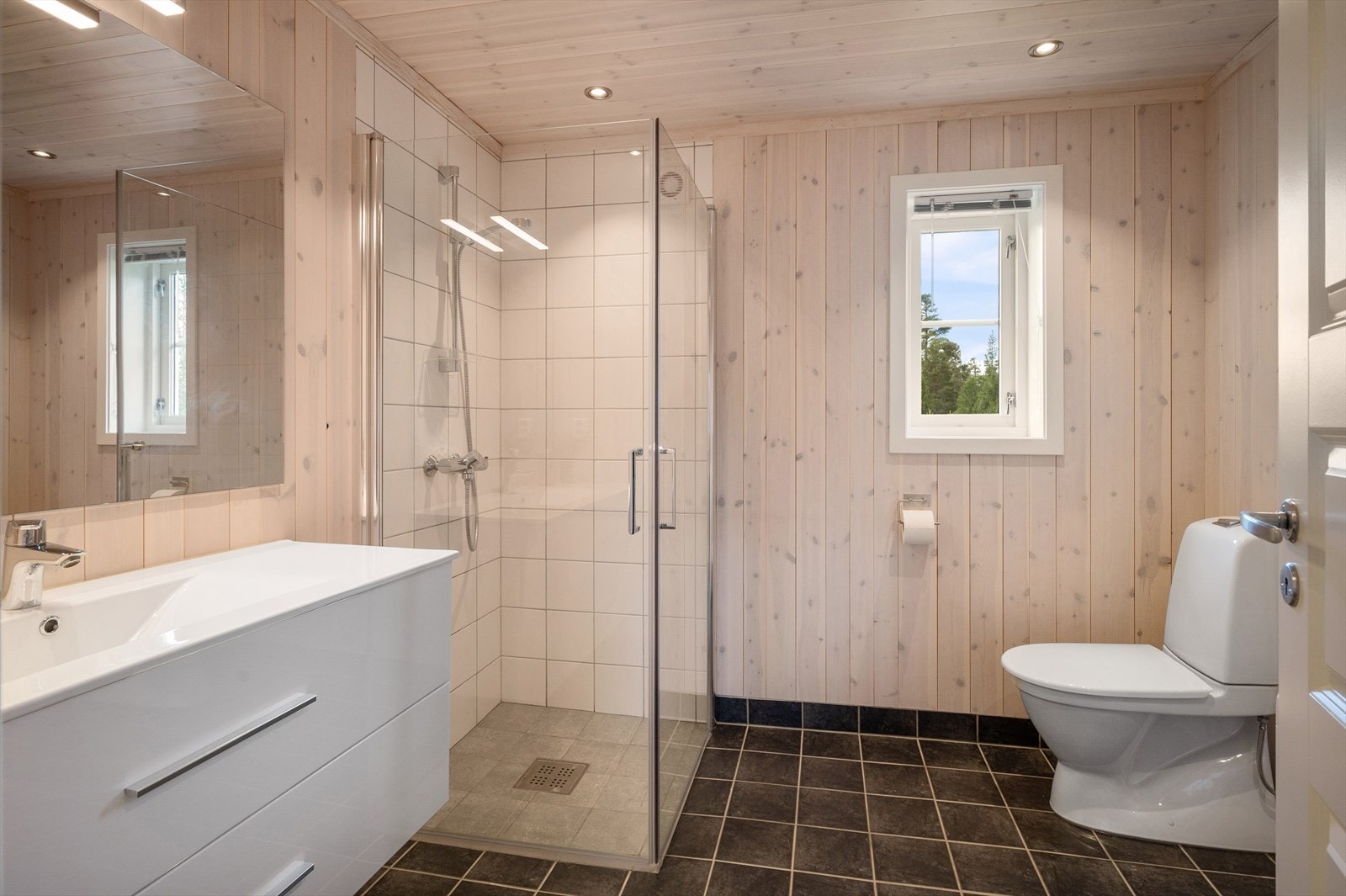 Romslig bad med hvit innredning, dusjvegger og wc. Galleribilde