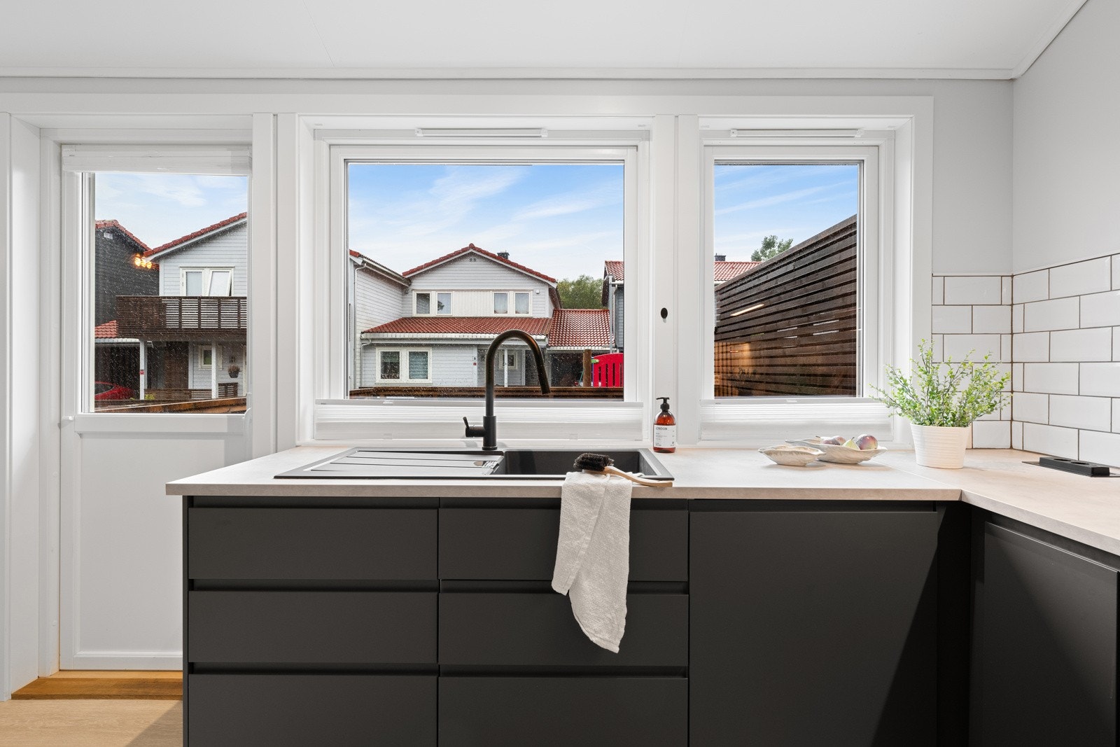 Her er det sorte, håndtaksløse fronter og lys benkeplate av laminat med grå oppvaskkum. Galleribilde