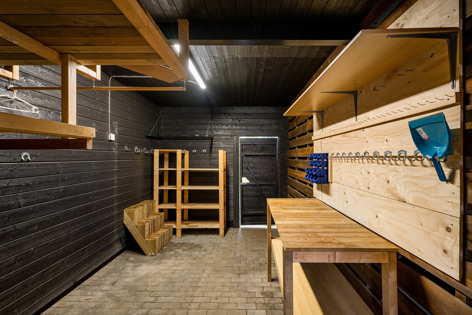 I bakkant av carporten er det en stor utebod med hyller og dør ut til hagen. Galleribilde