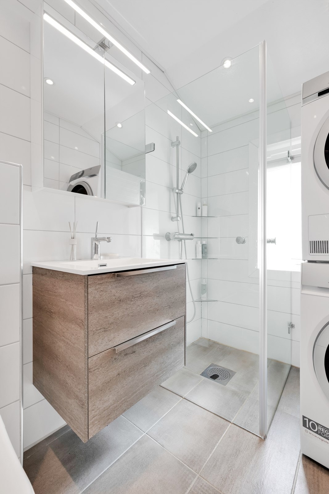 Innredningen består av et underskap/overskap, servant, speil, lys, stikk og en dusjsone med dusjing direkte på gulv og vegg. Galleribilde