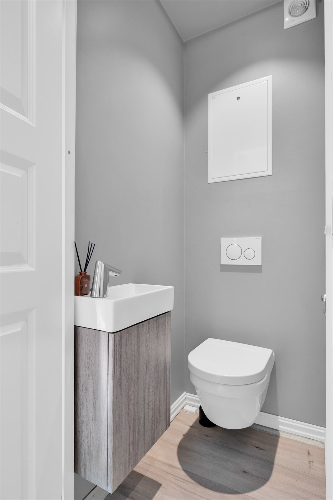 Separat toalettrom med laminatgulv og malte glatte veggoverflater. Innredningen har et underskap med servant og vannklosett. Det er montert downlights i himling. Galleribilde