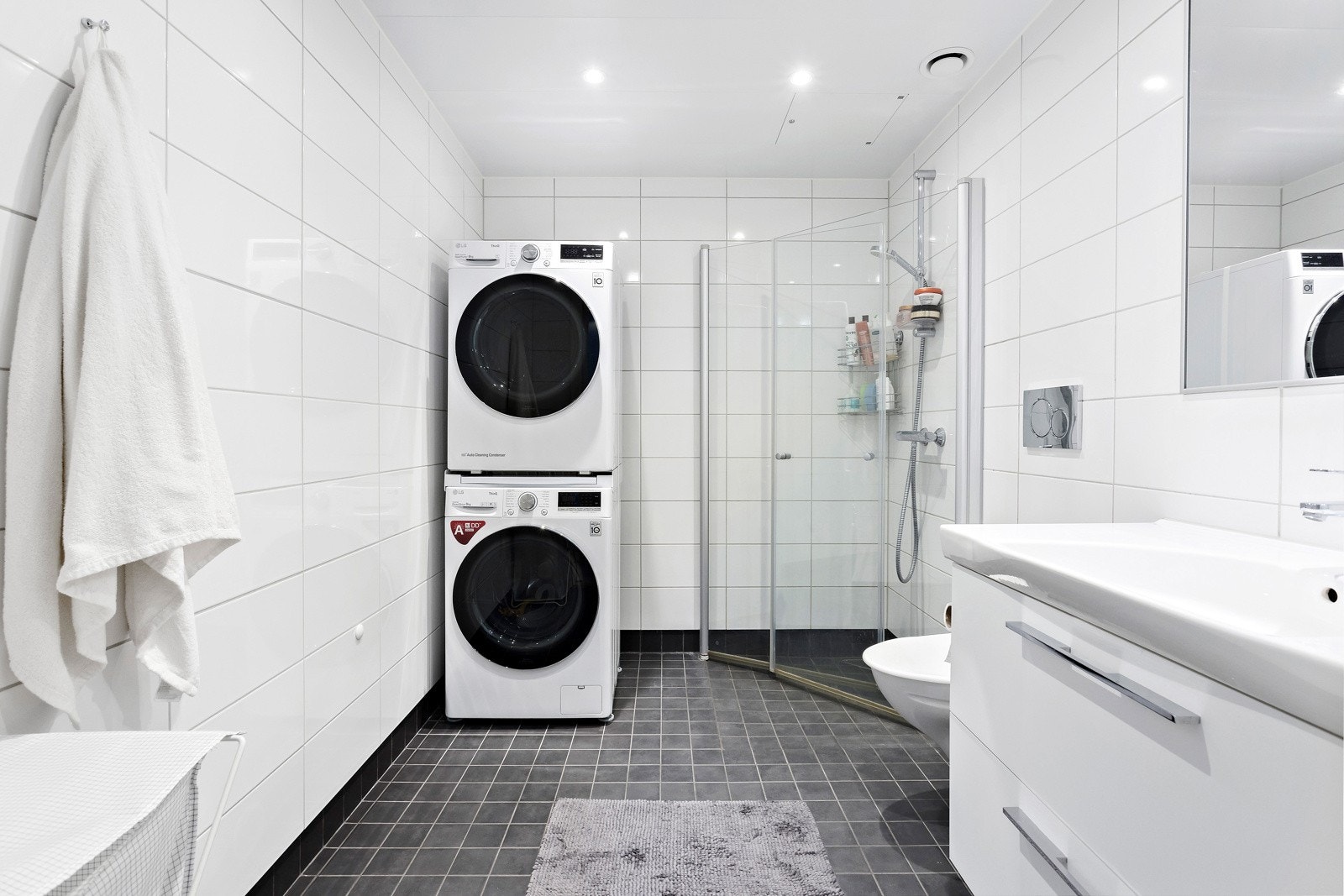 Badet består av flis på gulv og vegger og hvite metallplater i tak. Badet har varmekabler i gulv og opplegg for både vaskemaskin og tørketrommel. Galleribilde