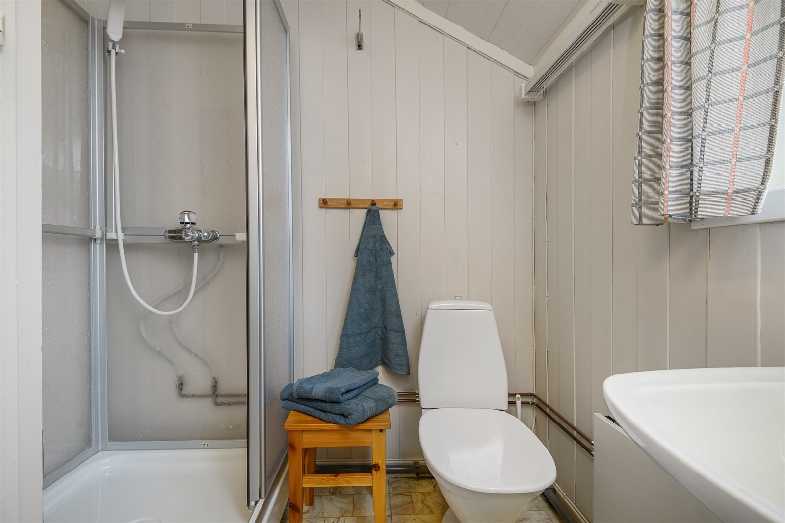 Lyst og hyggelig bad/wc med dusjkabinett, servant og vaskekum. Galleribilde