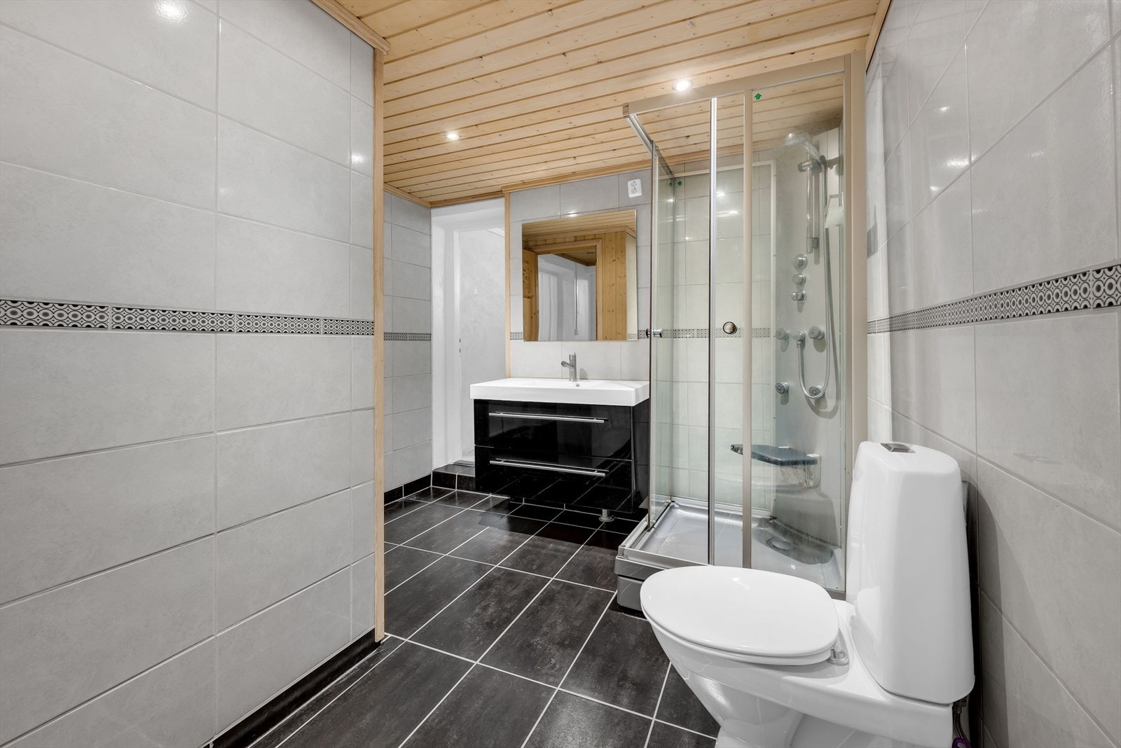 Helfliset bad fra 2011 med dusjkabinett, servantinnredning og toalett. Galleribilde