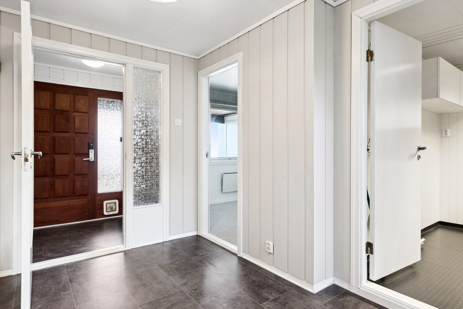 I hoveddelen er det et praktisk vindfang med adkomst til gangen. Begge rommene har gulvbelegg og malte panelvegger. Galleribilde