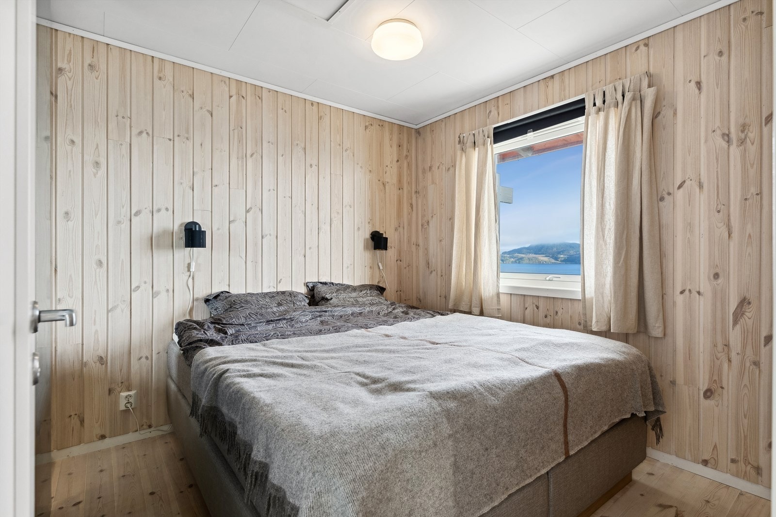 Hovedsoverommet ligger i første etasje, har tregulv, trepanel på veggene og vindu vendt mot sjøen. Galleribilde