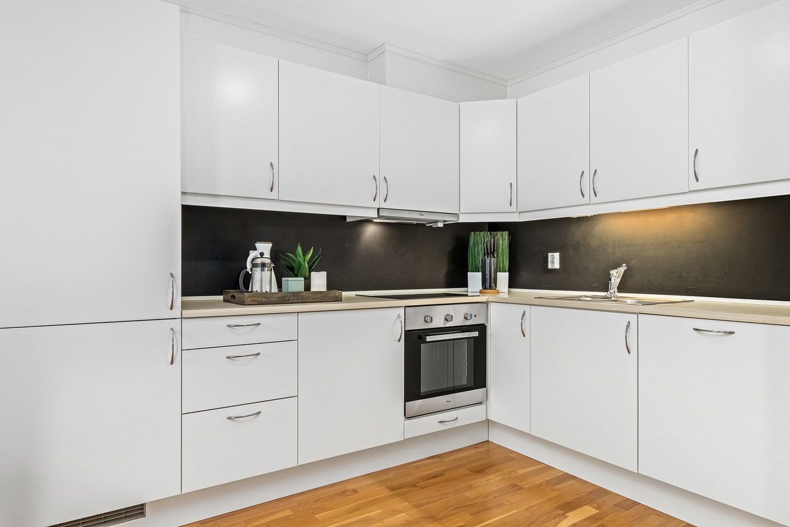 Pent kjøkken med integrert komfyrtopp, stekeovn, oppvaskmaskin, kjøleskap og fryseskap. Galleribilde