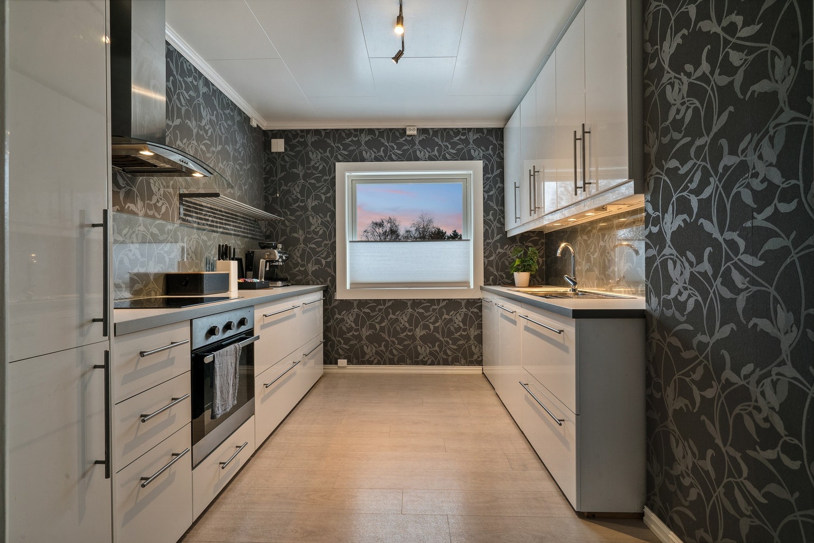 Stilrent og moderne kjøkken med integrerte hvitevarer, som består av kjøle- og fryseskap, oppvaskmaskin, induksjonstopp og stekeovn. Galleribilde