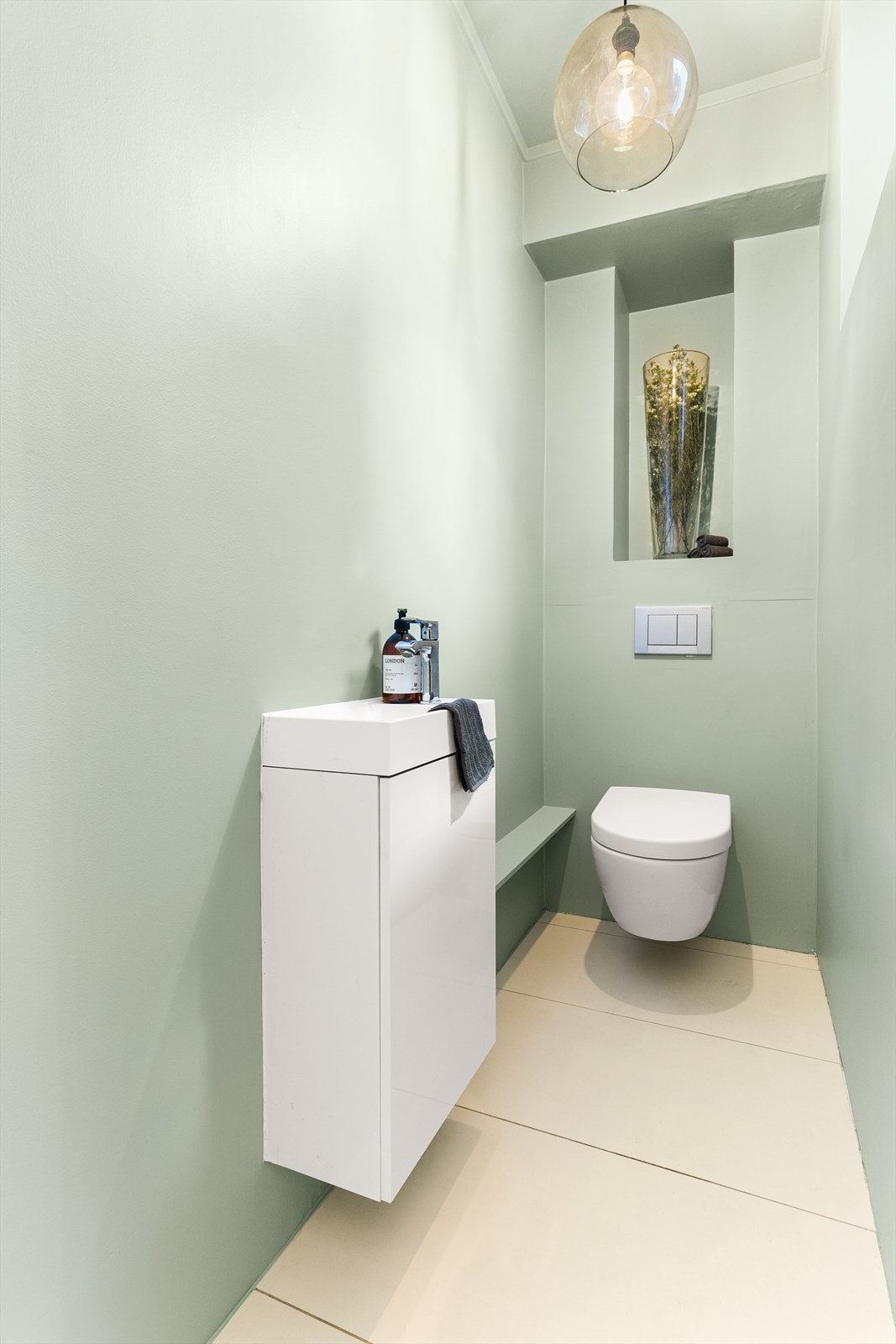 I tilknytning til entreen har man et lekkert gjestetoalett fra 2018 med fliser på gulv og ellers malte vegger. Rommet er utstyrt med veggmontert toalett, servant med underskap. Galleribilde