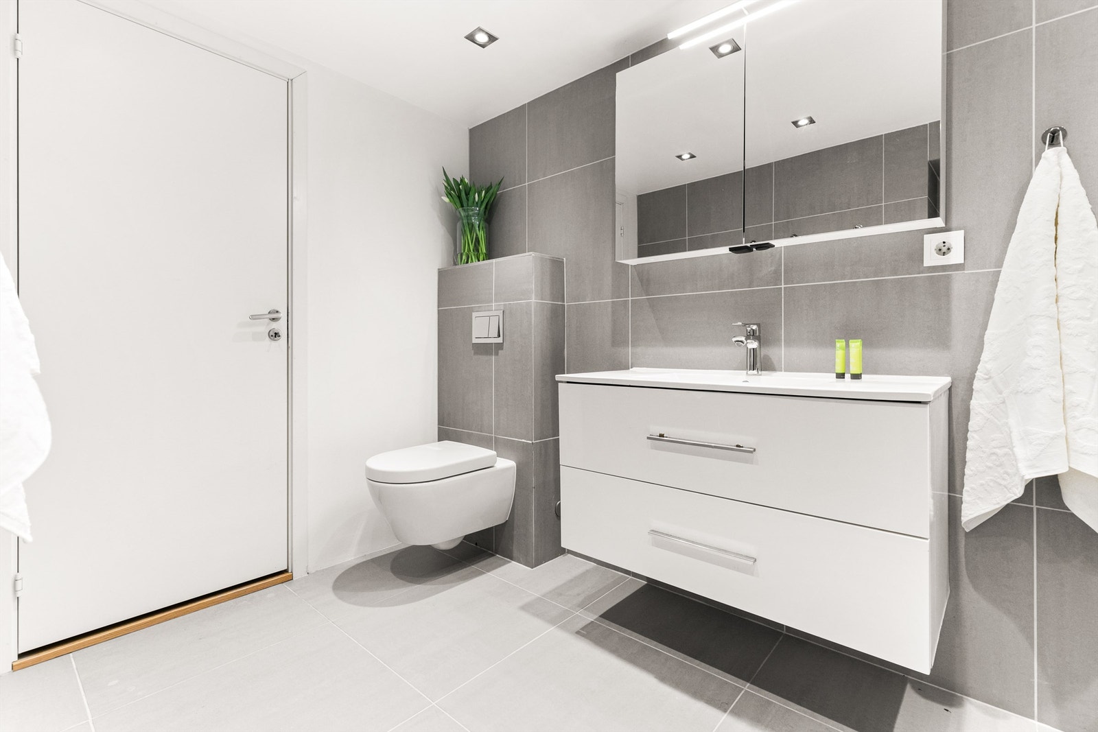 Badet er av god størrelse og er innredet med heldekkende servant, skapspeil med overbelysning, vegghengt toalett og badekar. Gir definitivt et stilrent uttrykk med 60x60 fliser også fra Marazzi på vegger- og gulv. Galleribilde