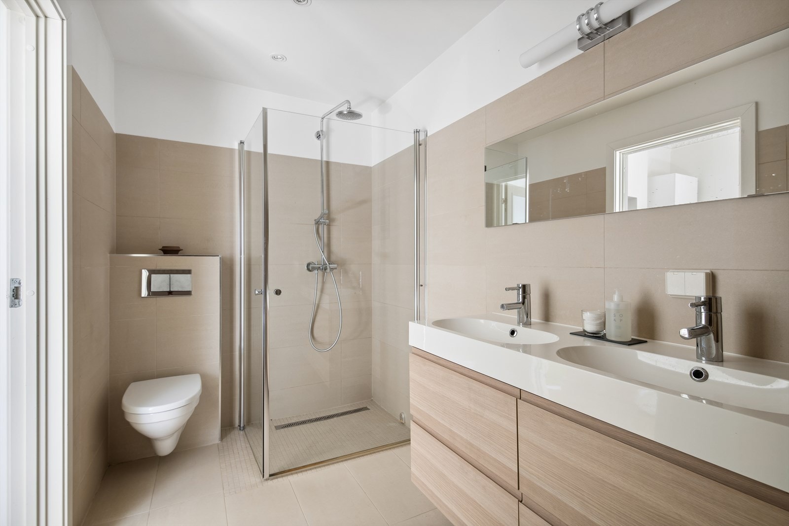 Badet er pent og delikat flislagt, med varmekabler i gulvet. Dobbel vask og vegghengt toalett med innebygget sisterne. Galleribilde