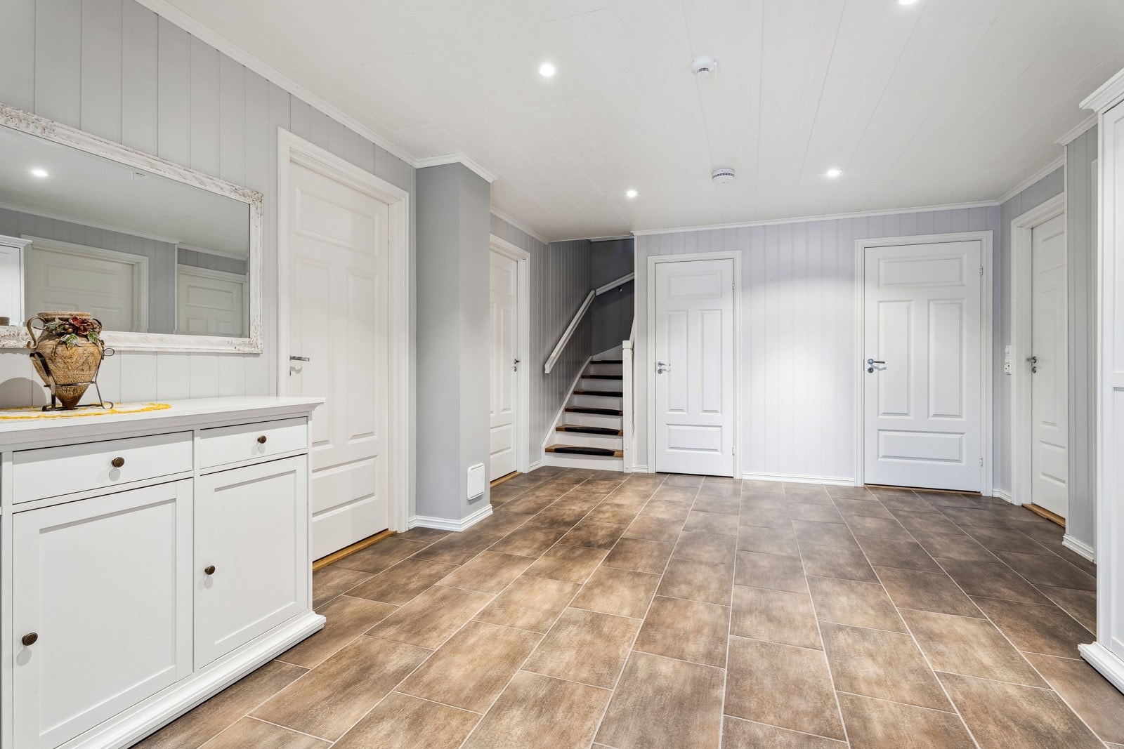 Hallen er romsleg og innbydande med downlights og flislagt golv Galleribilde