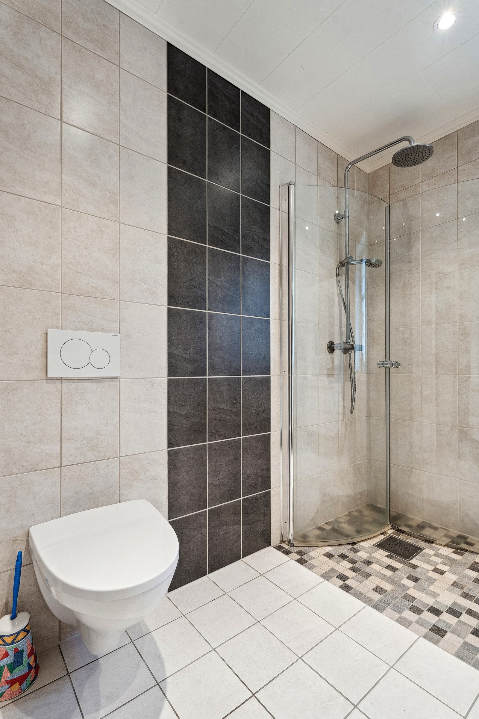 Badet er utstyrt med vegghengt wc, dusj og stor baderomsinnreiing. Galleribilde