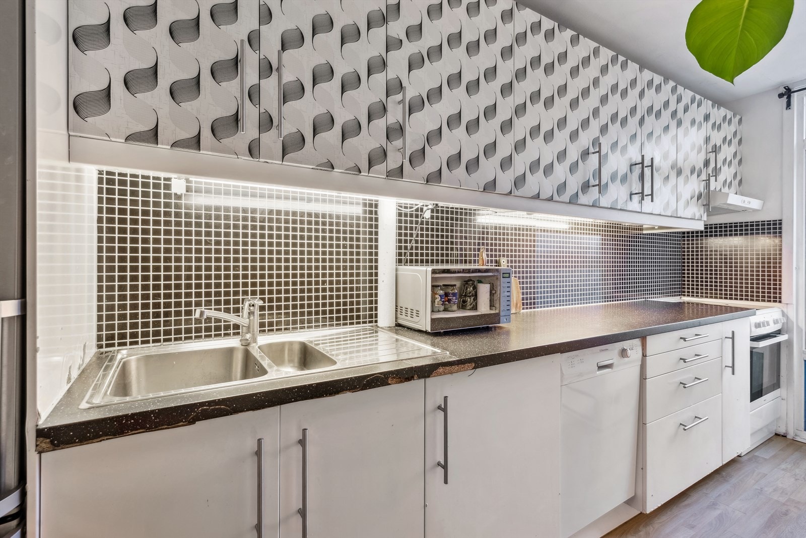 Innredningen har slette fronter og laminert benkeplate og mosaikkfliser beskytter bakveggene Galleribilde