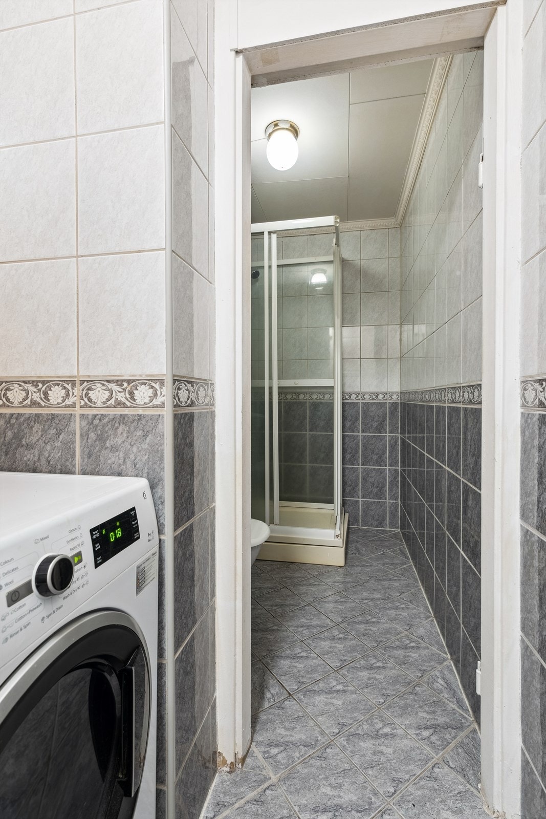 Flislagt bad delt i to avdelinger hvor den første delen har opplegg og plass til vaskemaskin Galleribilde