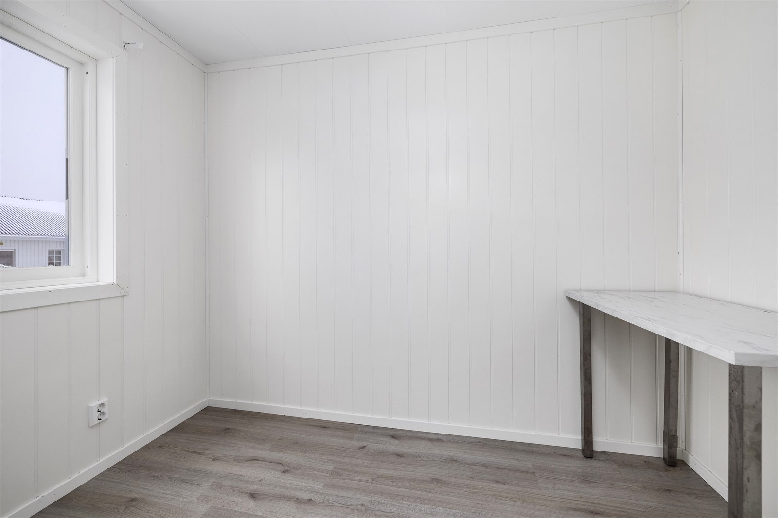 Kontoret har lysmalte vegger og laminat på gulv. Galleribilde