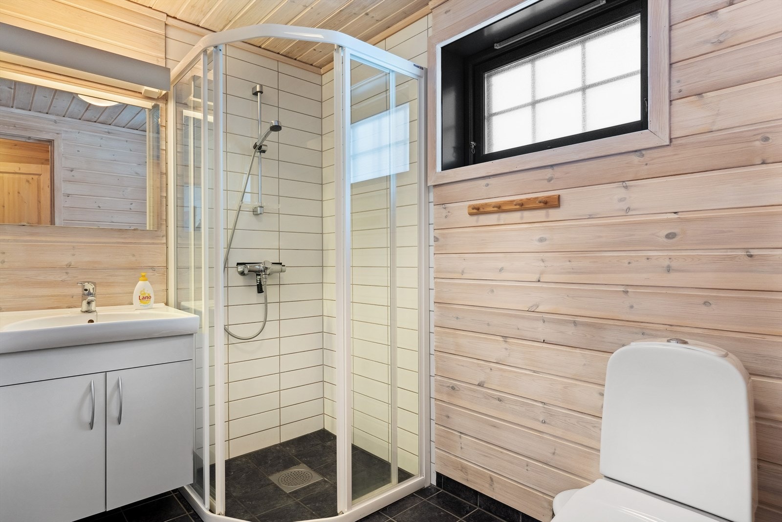 Badet har vegger med trepanel, og fliser i dusjhjørne, samt fliser på gulv med varmekabler. Galleribilde