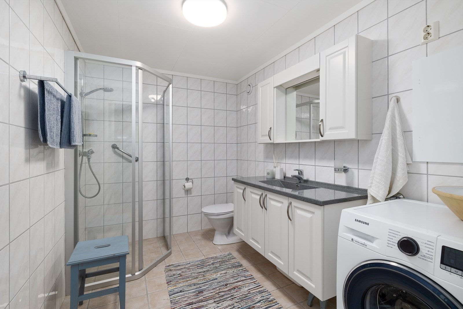 Flott bad med fliser på gulv og vegg. Inneholder baderomsinnredning med nedfelt servant, opplegg til vaskemaskin. Galleribilde