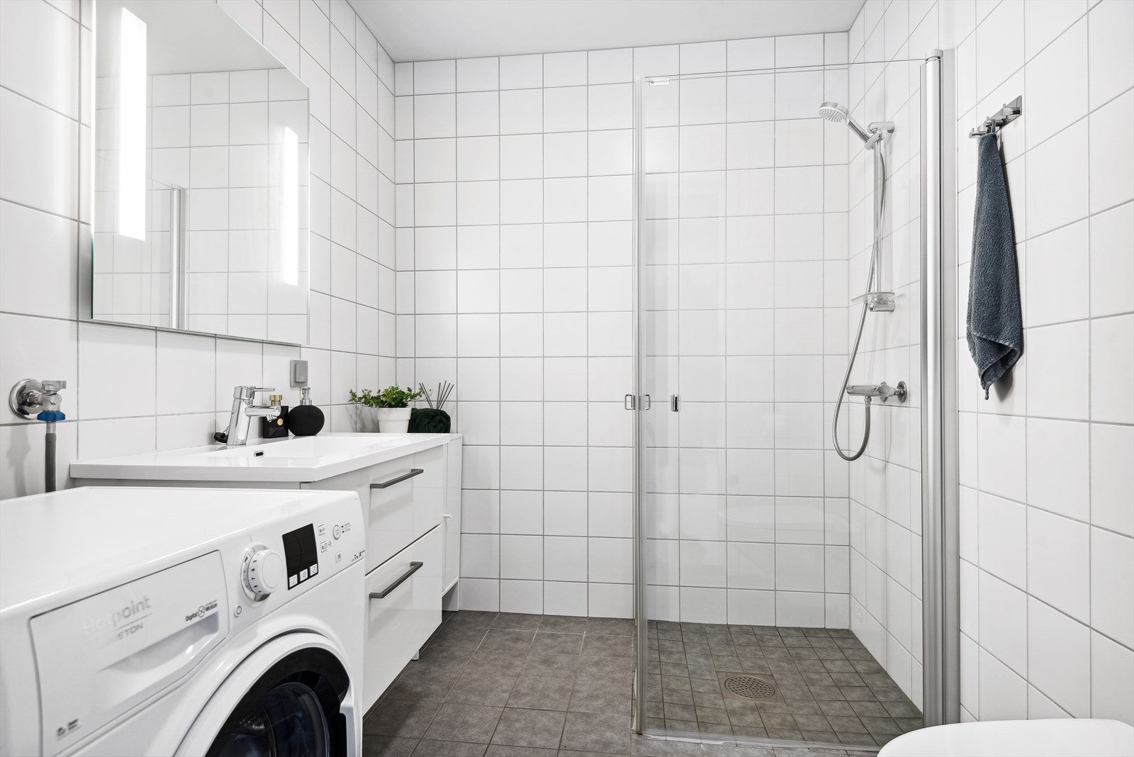 Flislagt baderom med varme i gulv. Rommet er innredet med servant over innredning, speil med belysning, dusjvegger, vegghengt toalett og opplegg for vaskemaskin. Galleribilde