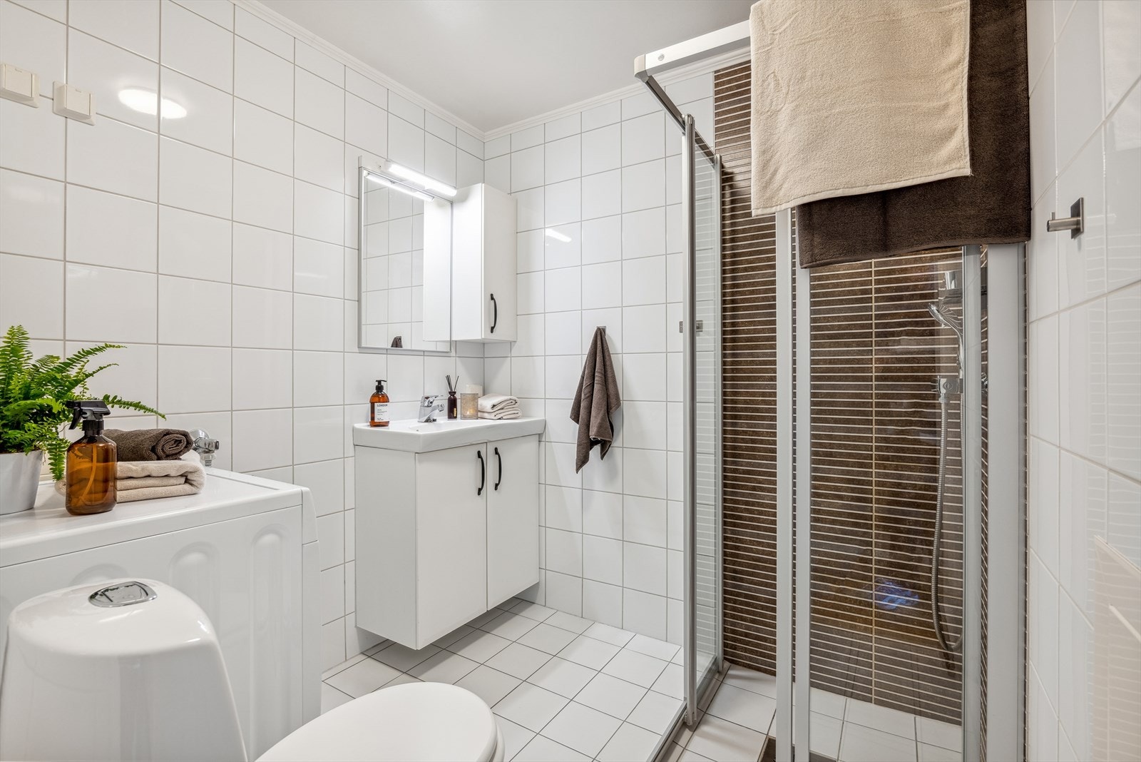 Pent flislagt bad fra 2008 med dusjhjørne, wc, speil- og servantskap. Galleribilde