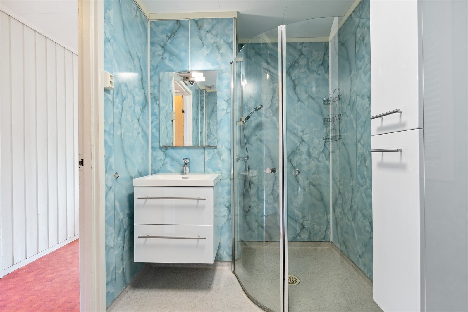 Rommet har dusjvegger, toalett, baderomsinnredning med servant og opplegg for vaskemaskin. Galleribilde