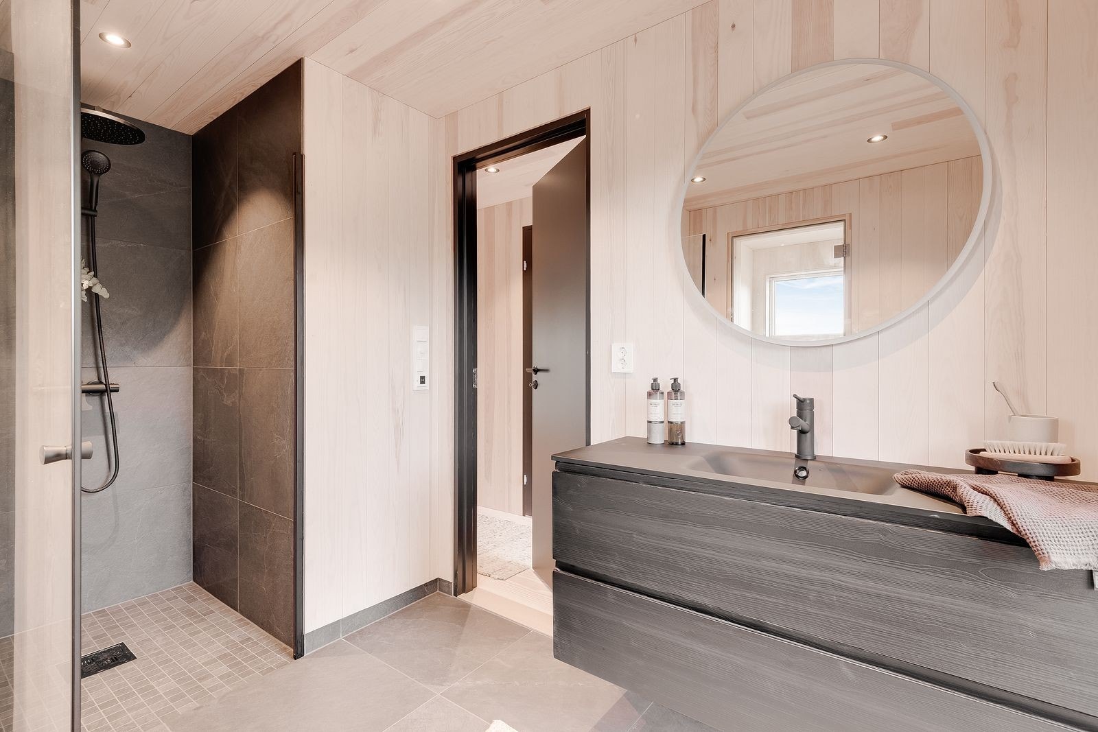 Stort bad med badstue, man kan hoppe rett ut i snøen gjennom dør på badet. Moderne innredning fra Vikingbad og speil med integrert belysning. Dyb dusjnisje med svart dusjarmatur Galleribilde