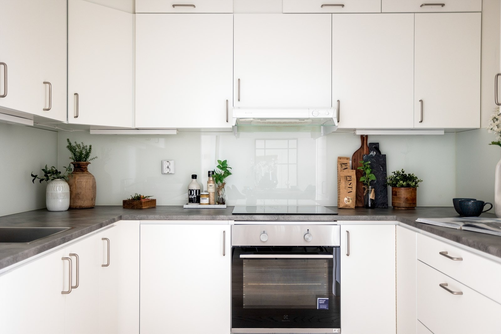 Laminat benkeplate med nedfelt kum i rustfritt stål, ventilator, induksjonstopp, stekeovn, oppvaskmaskin og kjøl/frys er integrert i innredningen Galleribilde