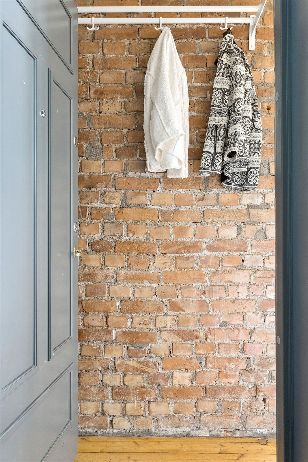 Via felles inngangsparti ønskes du velkommen inn i leilighetens entrè. Her blir du møtt av en sjarmerende teglsteinsvegg som gir et godt førsteinntrykk. Galleribilde