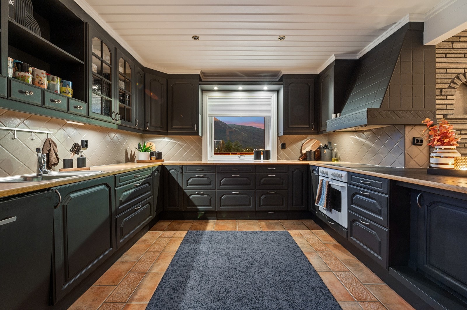 Et romslig eikekjøkken malt i dempet sort. Galleribilde