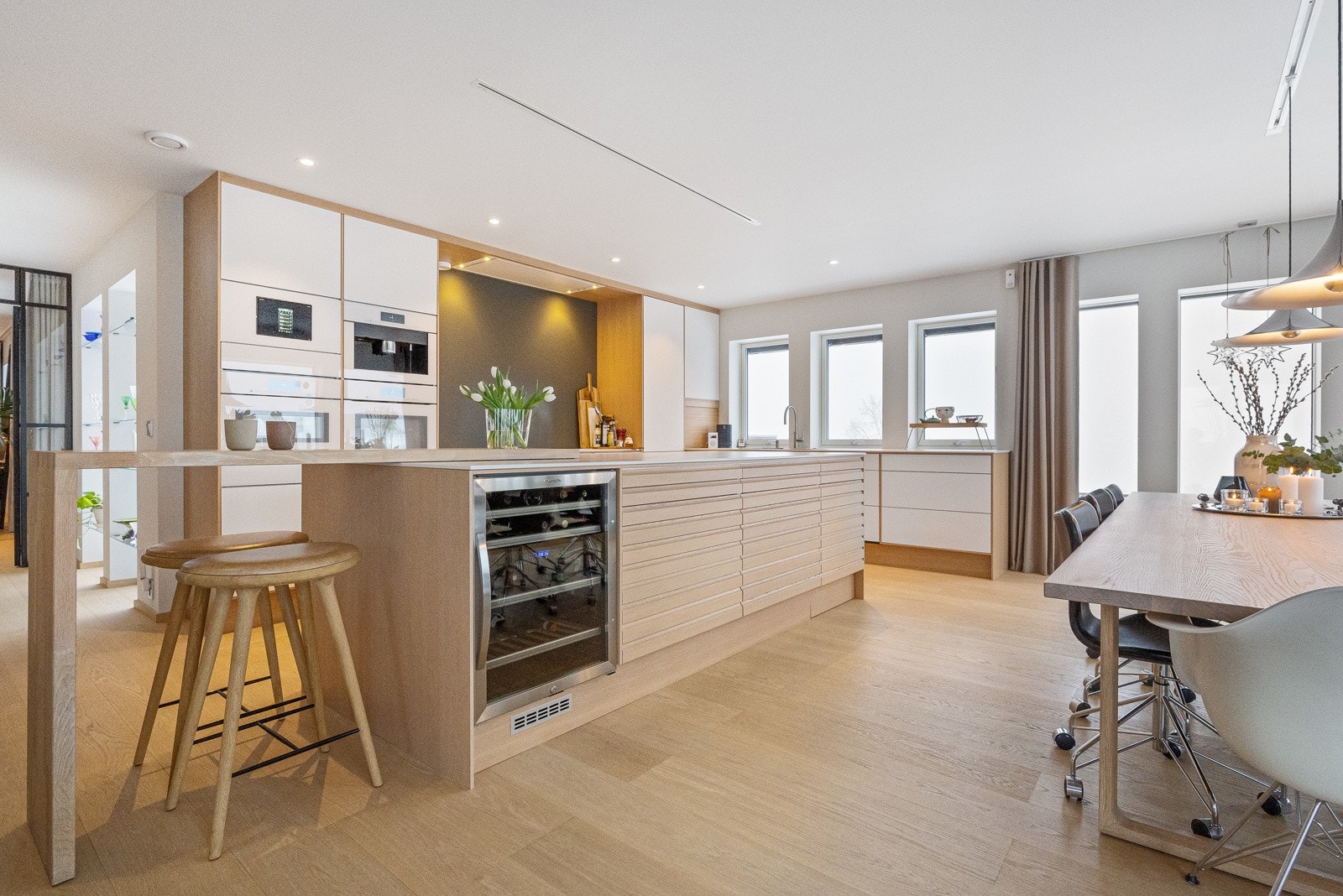 Moderne kjøkken med integrert komfyr, koketopp, fire kjøleskuffer, oppvaskmaskin, dampovn, kaffemaskin og vinskap Galleribilde
