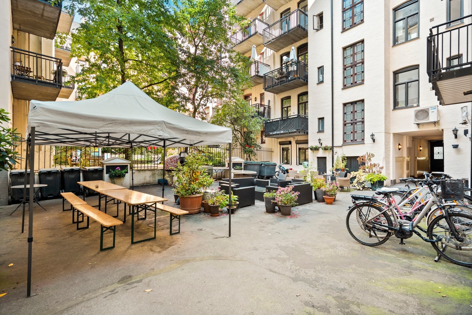 Asfaltert bakgård, sittegrupper, vedfyrt pizzaovn, sykkelparkering og diverse beplantinger Galleribilde