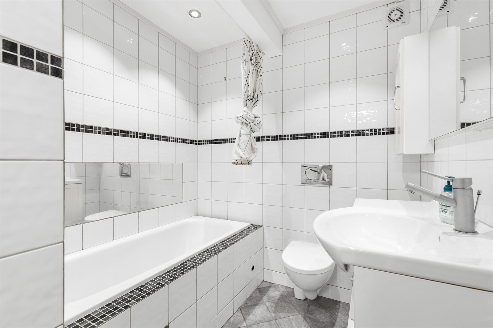 Bad underetasje. Badekar og vegghengt toalett. Noe flisbom og sprukket flis på vegg. Rommet er ikke omsøkt/godkjent til varig opphold. Galleribilde